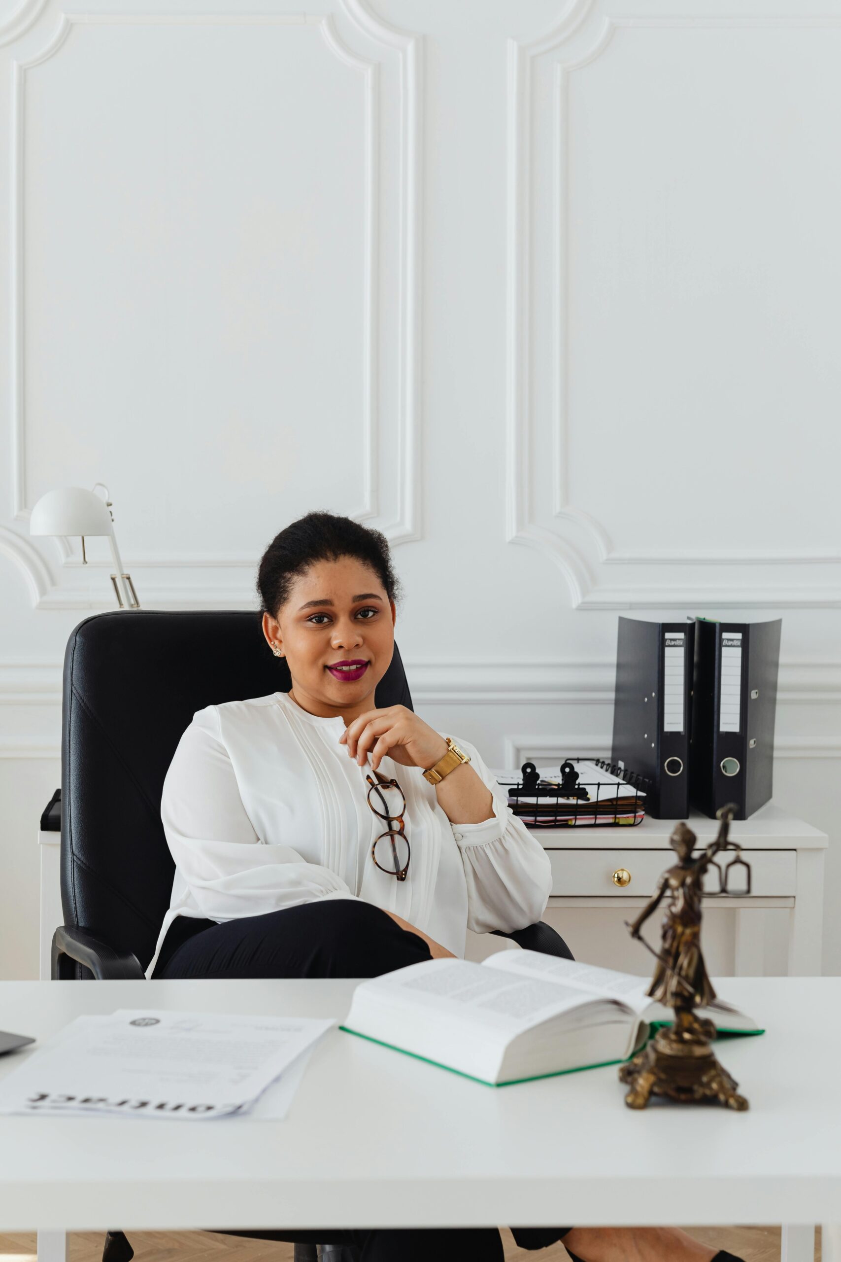 Professional woman sitting at desk in a stylish office, exuding confidence and leadership.